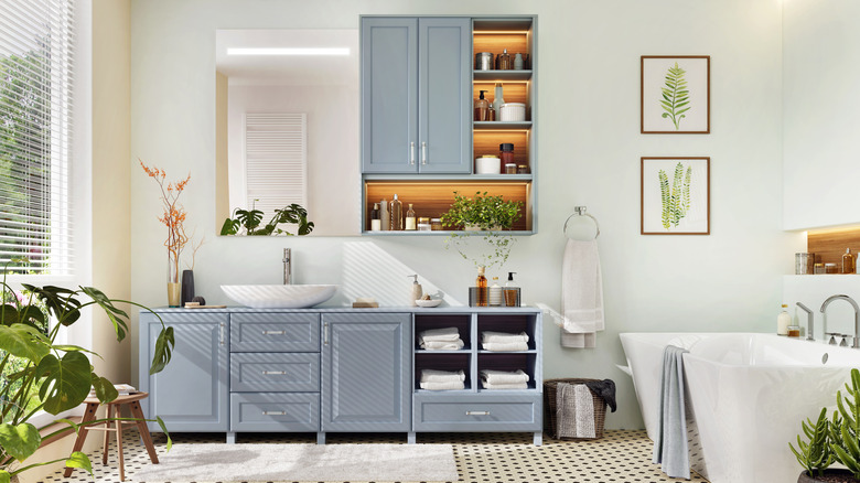 A bathroom with light blue cabinetry, white walls, and a stand alone tub.