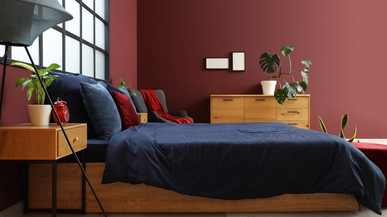 A bedroom with navy sheets and burgundy walls