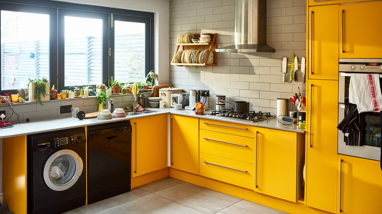A bright kitchen with yellow cabinets, oven, and fridge