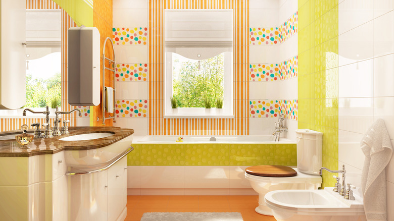 A bold, colorful bathroom with striped wallpaper and various yellow and orange tiles
