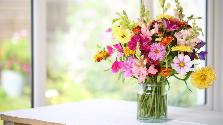 Vase on table with colorful variety of flowers, including regular cosmos and the double click variety.