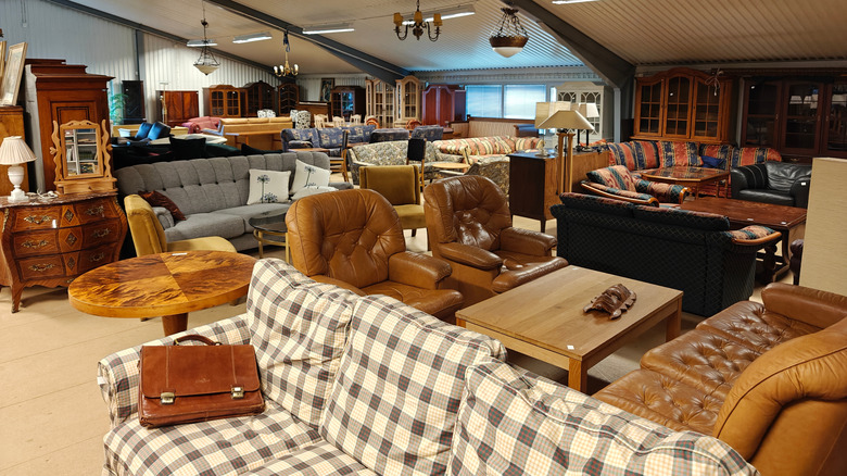 A second-hand thrift store crowded with furniture, including couches, coffee tables, and armchairs