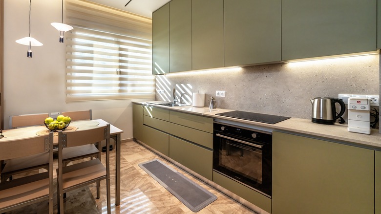 Contemporary kitchen with cabinets painted in a warm olive green paint
