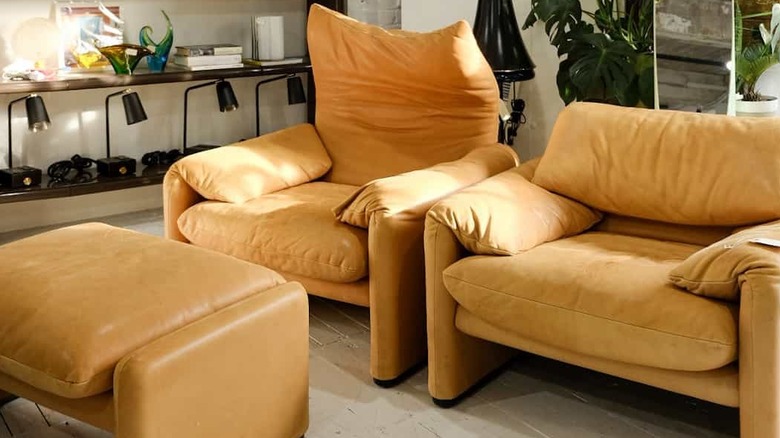 Two Maralunga lounge chairs and an ottoman in a living room with bookcases in the background