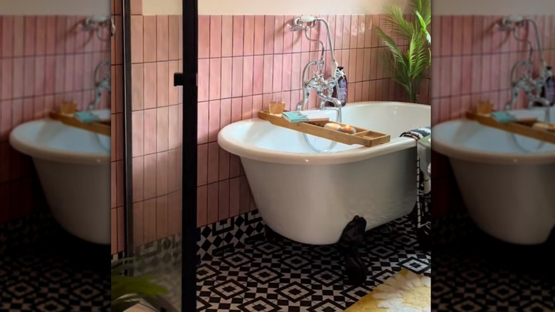 A bathroom with pink wall tiles and Moroccan floor tiles and a claw foot bath.