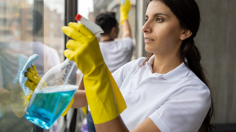 person using windex glass cleaner