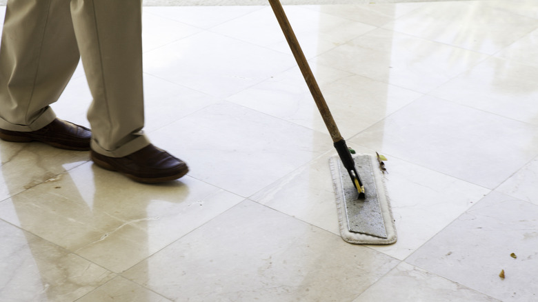 Man dust-mopping a marble floor