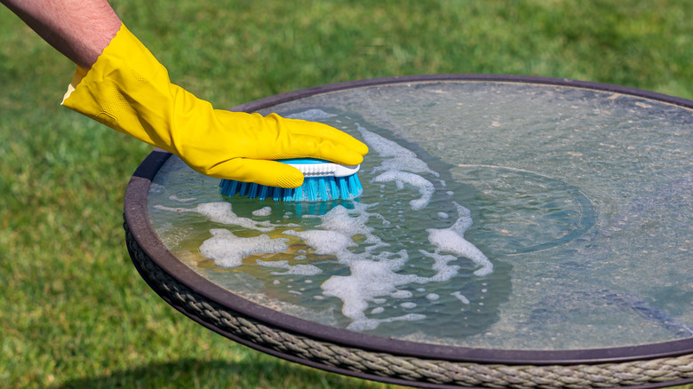 person scrubbing dirt off a dusty outdoor table