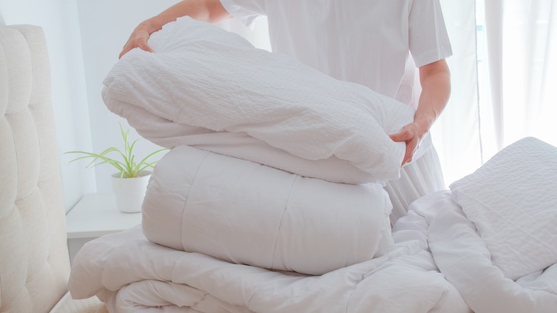 Close up of person folding white bedding