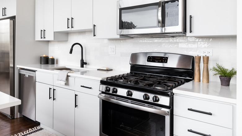 White kitchen with black and stainless gas stove.
