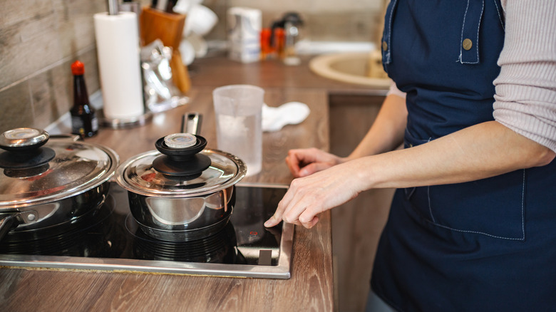 Person adjusting temperature on induction cooktop while cooking