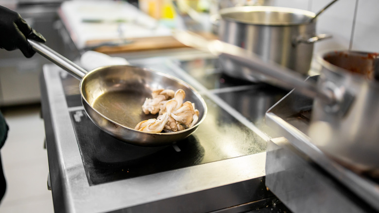 Hand picking up pan from induction cooktop burner