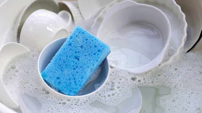 Dishes soaking in sink with sponge