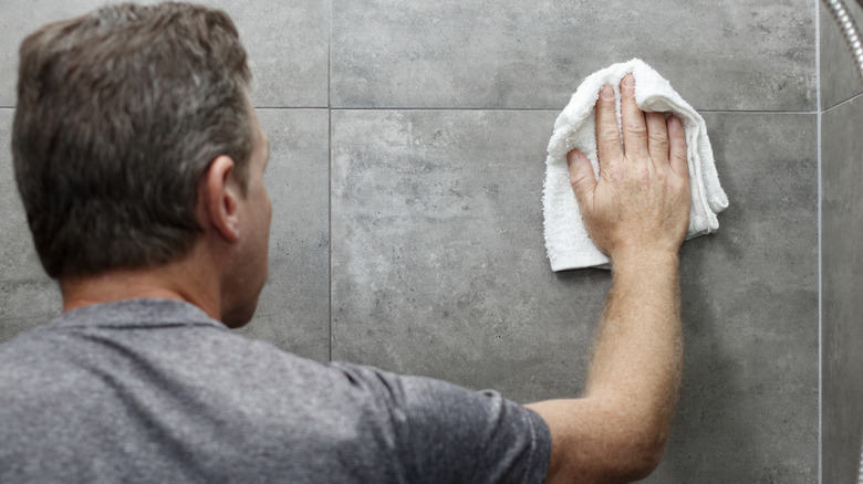 Man wipes shower tile