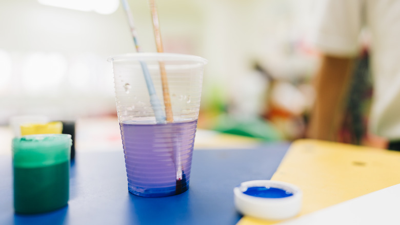 plastic cup holding acrylic paint water on artist's table