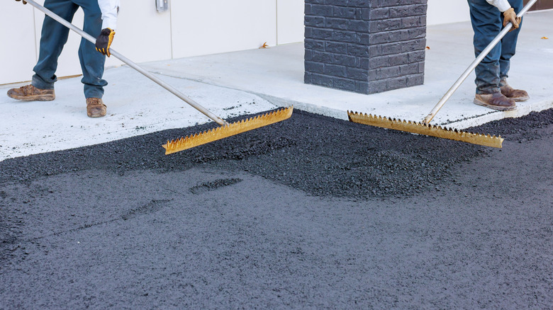 Workers leveling a new asphalt driveway