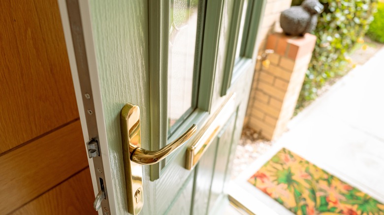 Close up of brass front door handles of a home, green door