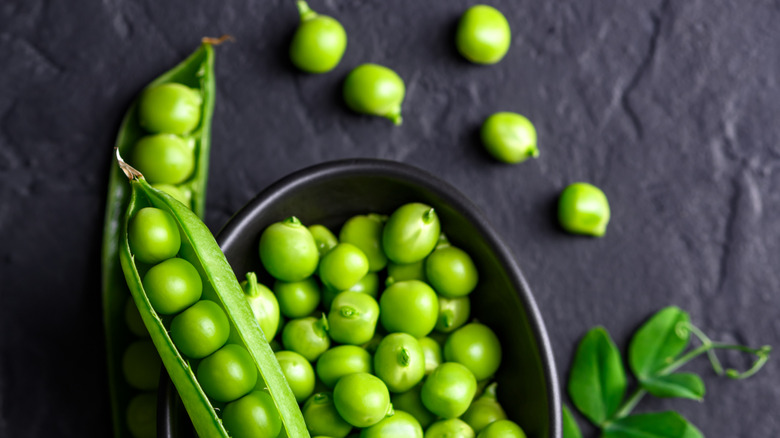 Fresh green peas in a black bowl