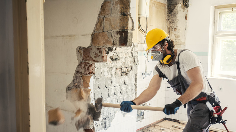 A construction worker knocking down a wall