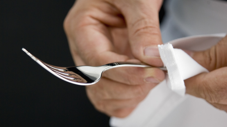 Hand wiping silver fork