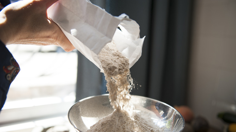 Person pouring flour into a bowl.