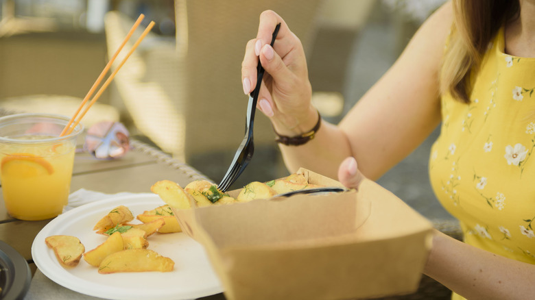 Someone eating with disposable cutlery
