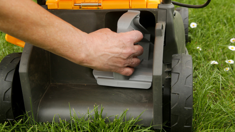 Person inserting a mulching plug in a walk-behind mower
