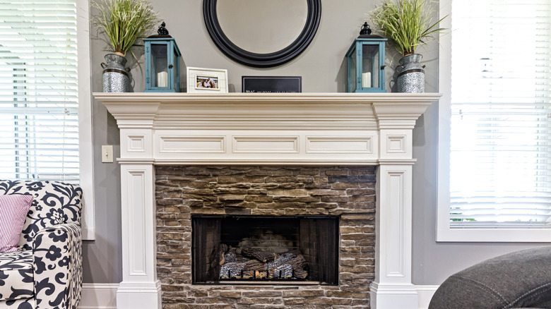 A mantel with large planters, lanterns, and smaller decor
