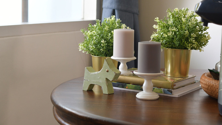 Books stacked on a table with planters, candles, and decor