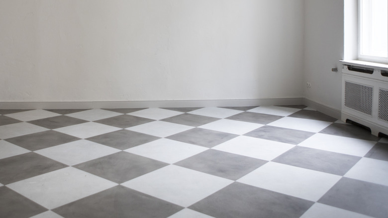 A clean, empty room with white walls and a grey and white diamond pattern floor.
