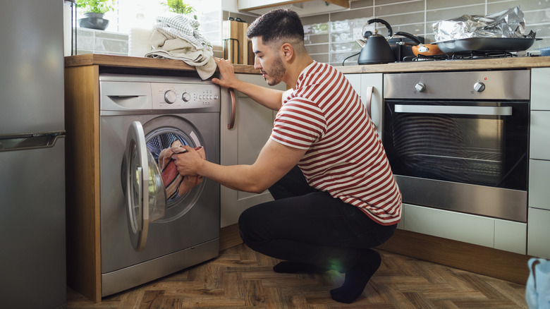 man putting laundry in washer