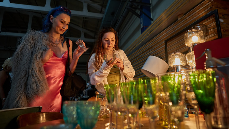 Two women shopping for thrifted glassware