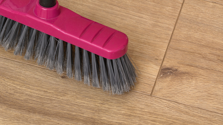 A broom cleaning a vinyl floor