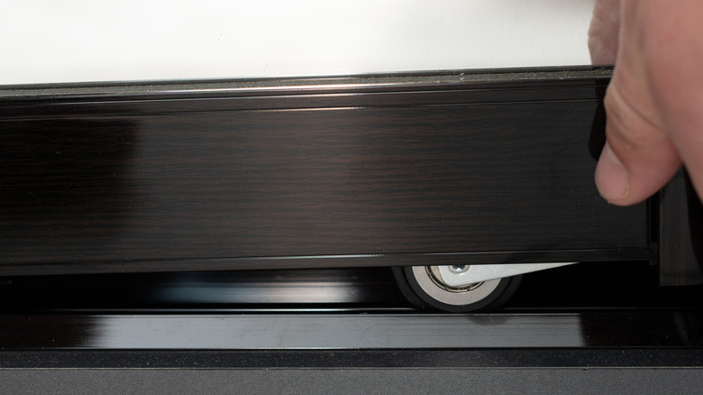 A close up of a closet door wheel on track
