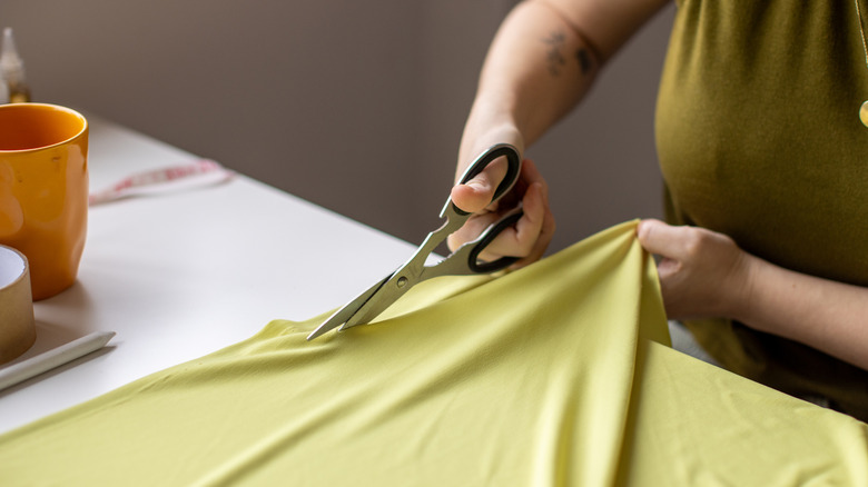 A woman cutting material with a pair of scissors