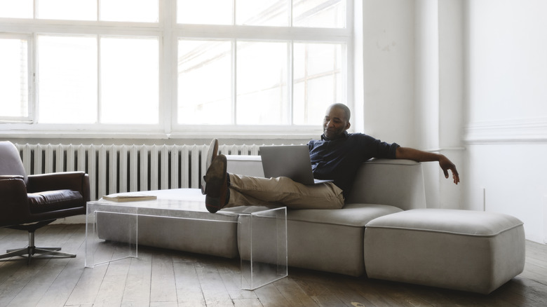 Man with laptop sitting on couch in minimalist living room