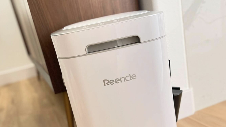 A white Reencle electric composter sits on the floor of a kitchen