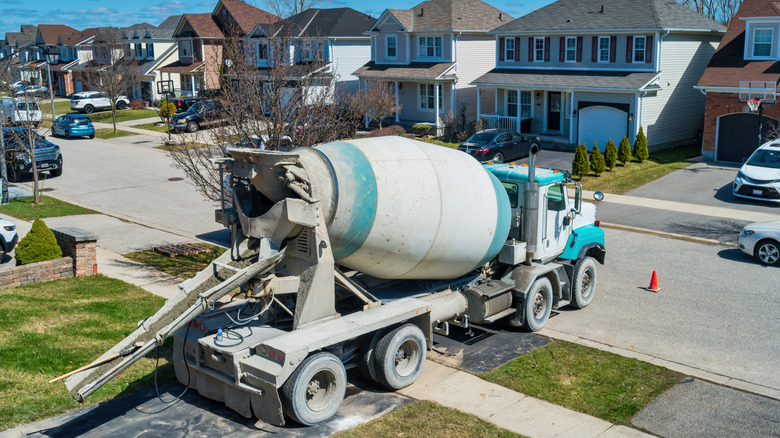 A cement truck backing up in a suburban neighborhood to pour a new concrete driveway.