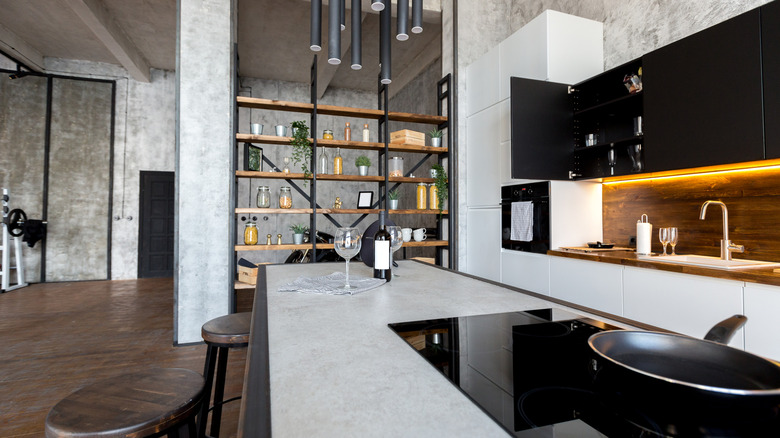 Industrial style kitchen with concrete walls, modern lighting, sleek countertops.