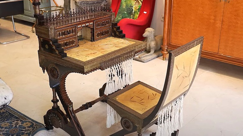 A chair and table by Carlo Bugatti displayed in an antique store.