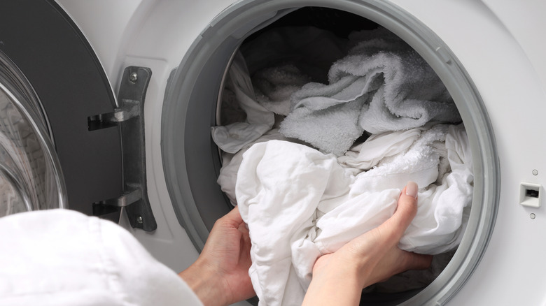 Hands taking clean laundry out of washing machine