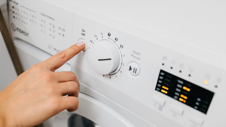Hand turning on and starting a washing machine
