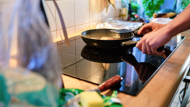 Person cooking in a frying pan on induction stovetop