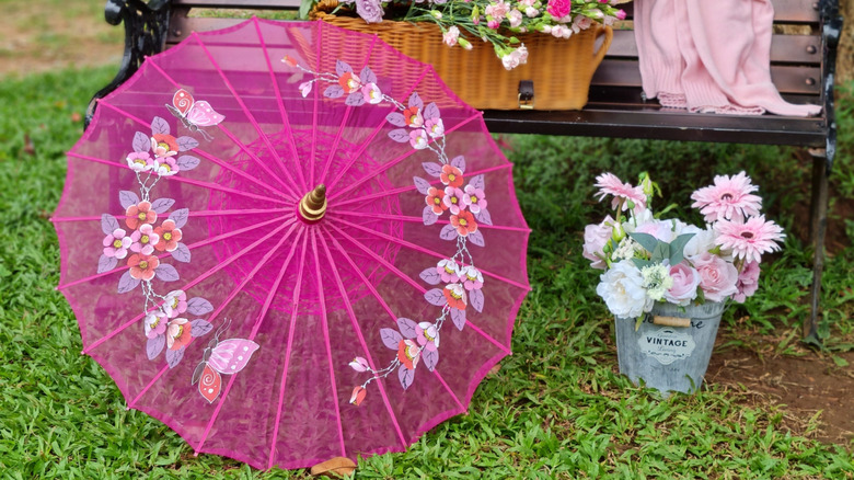 Vintage pink umbrella open on the ground near pink flowers