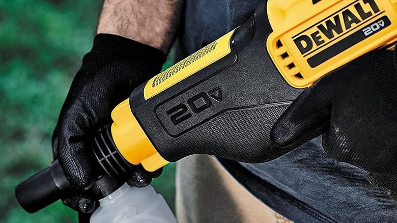 Person holding a DeWalt cordless power washer with a soap dispenser