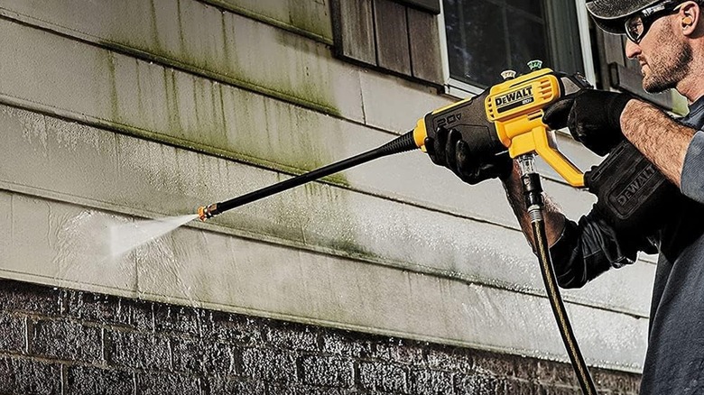 Man washing siding with a DeWalt cordless power washer