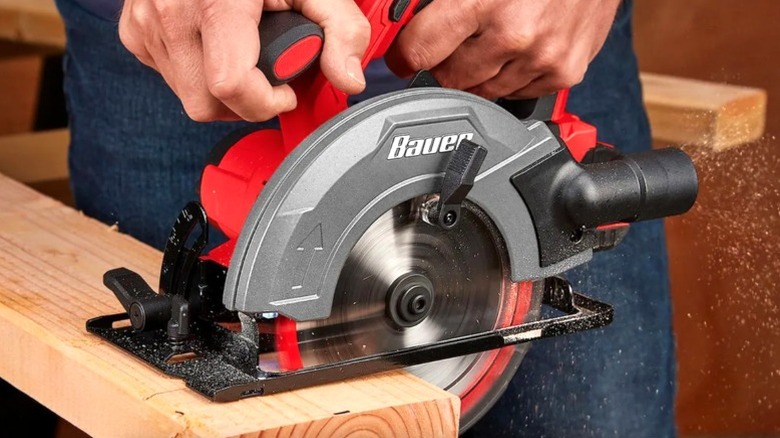 A person uses a cordless Bauer Circular Saw from Harbor Freight to cut lumber