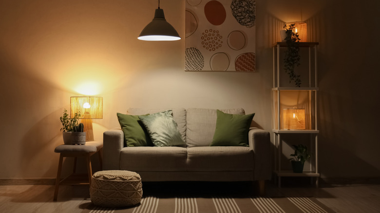 A living room with balanced lighting from a table lamp, hanging pendant, and small accent lights.