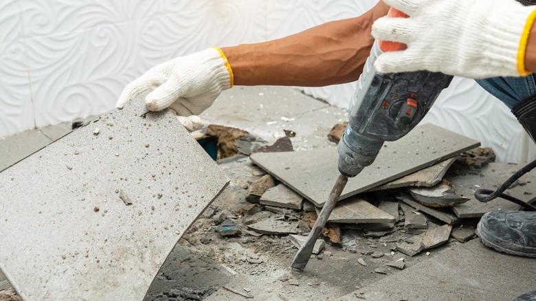 person removing old ceramic tiles