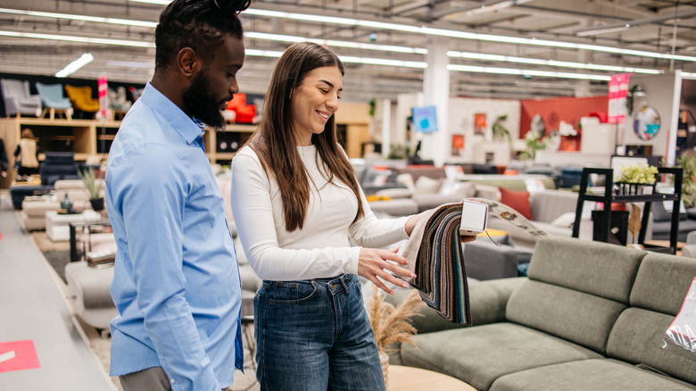 A happy biracial couple shops for new living room furniture.
